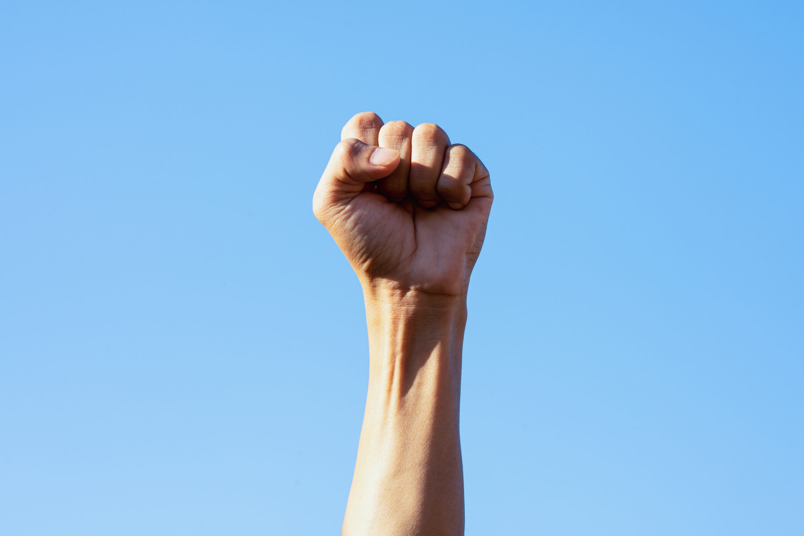People raise fist up, sky background (Photo by Worawut via Adobe Stock)